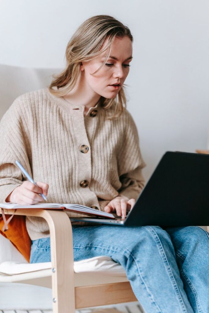 Boost Your Productivity with These 7 Effective Online Study Methods Serious female freelancer taking notes in notepad while looking at screen of netbook while sitting in armchair on white background